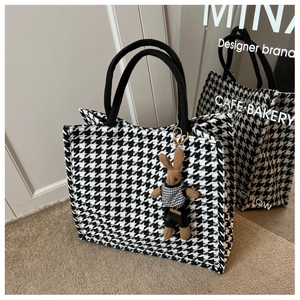 Detail of houndstooth tote bag featuring a cute brown rabbit plush charm and woven handles