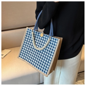 Detail of blue houndstooth tote bag featuring pearl handle and wooden button closure