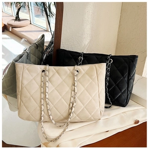 Detail of large quilted tote bags with elegant chain straps in black and beige colors