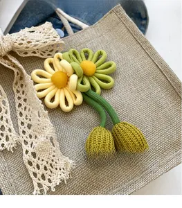 Detail of woven jute bag featuring 3D knitted yellow flowers and delicate lace bow
