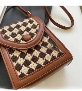 Detail view of houndstooth fabric texture and brown leather trim on crossbody bag