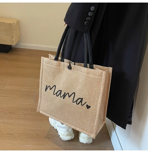 Detail of linen tote bag with black Mama script and heart print held by a model