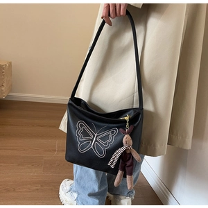 Detail of black pebbled leather tote bag with butterfly embroidery and rabbit charm