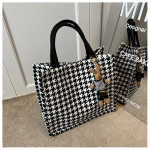 Close-up of houndstooth tote bag featuring rope handles and a cute brown rabbit pendant
