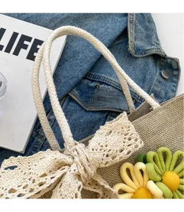 Detail of woven straw handbag with lace bow, floral charms and braided rope handle