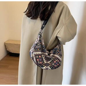 Close-up of ethnic style woven crossbody bag with geometric patterns on model