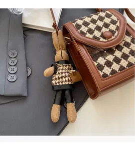 Detail of vintage houndstooth crossbody bag with brown leather trim and cute rabbit charm