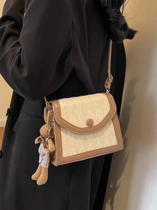 Sac bandoulière matelassé beige chic avec garniture en cuir brun et pendentif ours