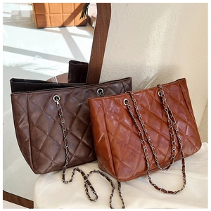 Quilted tote bags in dark brown and caramel leather with metal chain straps and ring details