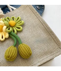 Detail of woven straw handbag featuring delicate knitted flower charm and textured fabric