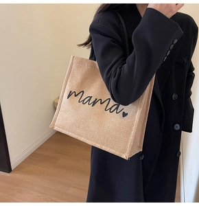 Close-up of beige linen tote bag with black mama print and heart detail showing texture