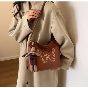 Detail of vintage tote bag with butterfly embroidery and cute plush rabbit charm