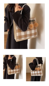 Detail view of large plaid linen tote bag with brown pom-pom cherry charm and rope handle