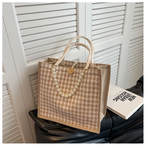 Detail of houndstooth tote bag featuring pearl chain strap and decorative wooden button