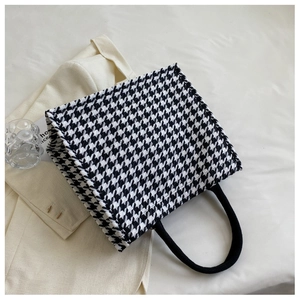 Detailed top view of a houndstooth tote bag featuring black rope handles and woven texture