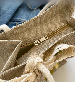 Detailed close-up of the jute tote bag metal zipper and decorative lace trimming