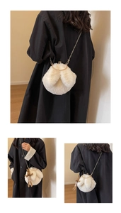 Detail view of white plush shell bag with gold clasp and chain strap on black coat