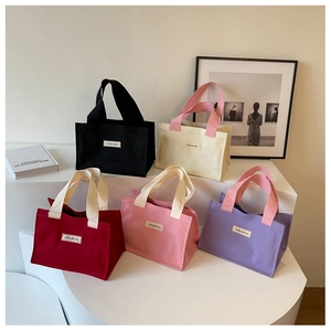 Vue détaillée de cinq sacs en toile de couleurs variées sur un présentoir blanc épuré