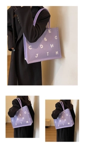 Close-up of the purple canvas tote bag with white letter print and woven texture detail