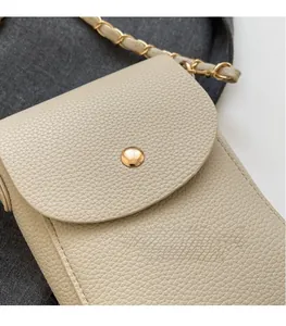 Nahaufnahme der beigen Handy-Tasche aus Litchi-Leder mit goldener Schnalle und Kette