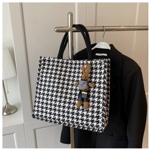 Detail of houndstooth canvas tote bag with a cute brown bunny charm and black straps