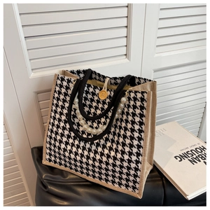 Detail of houndstooth tote bag featuring wooden button closure and pearl chain accent
