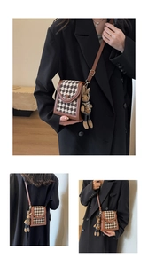 Detail of crossbody phone bag featuring houndstooth pattern and cute plush bunny charm