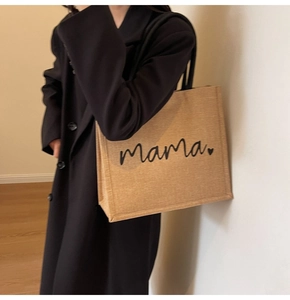 Close-up of large linen tote bag featuring mama text print and black round handles