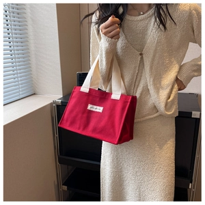 Détail du sac cabas en toile rouge avec étiquette FASHIONS BAG et anses tressées