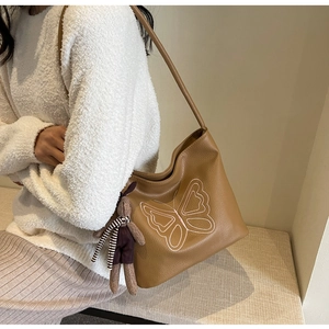 Detail of vintage brown tote bag with white butterfly embroidery and cute rabbit charm