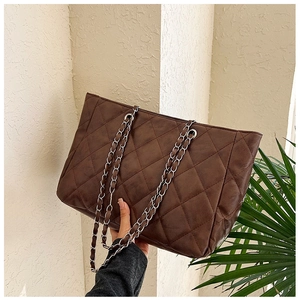 Detail of vintage brown quilted tote bag with metal chain strap and matte finish