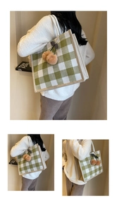 Detail of green and white waffle tote bag featuring a cute brown plush cherry pendant