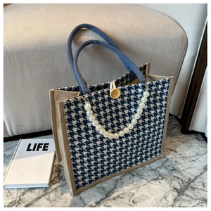 Detail of houndstooth tote bag with pearl chain decoration and woven rope handles