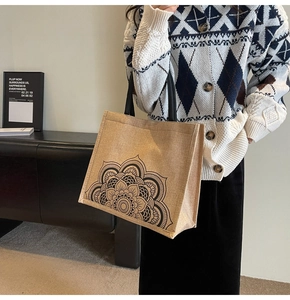 Close-up of a jute tote bag featuring a black mandala floral print and woven handles