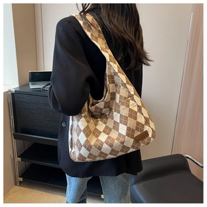 Detail of a spacious canvas tote bag featuring brown and white rhombic pattern and fashion label