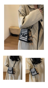 Detail of checkered crossbody phone bag featuring a plush rabbit charm and adjustable strap