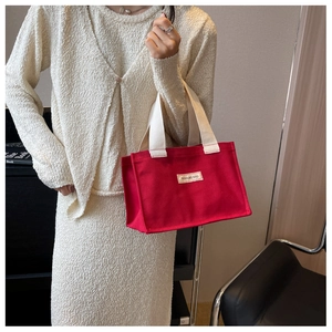 Détail du sac fourre-tout en toile rouge avec poignées blanc cassé et étiquette cousue