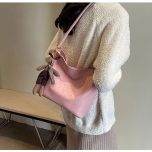 Detail of pink hobo tote featuring butterfly embossing and a cute bear charm pendant