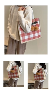 Detail of red gingham tote bag with plush cherry charm and linen trim texture