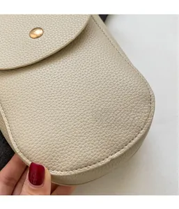 Detail der beigen Handytasche mit Litschinarbung und rundem goldenem Metallverschluss