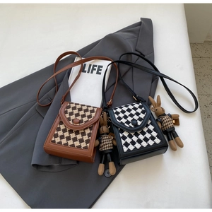 Detail of vintage tweed checkered crossbody bags with cute bunny charm accessories