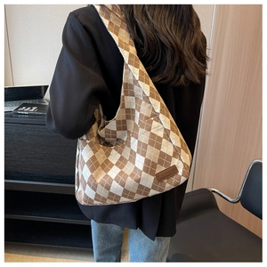 Detail of large brown argyle canvas tote bag featuring a leather Fashion patch on the side