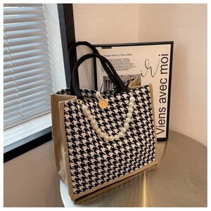 Detail of houndstooth tote bag with pearl chain accent and black woven handles