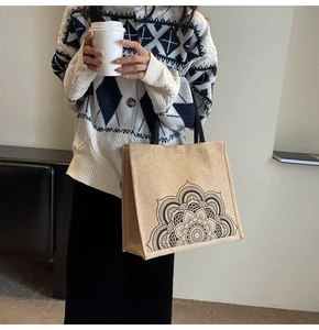 Detail of linen tote bag featuring black mandala floral print and durable web handles
