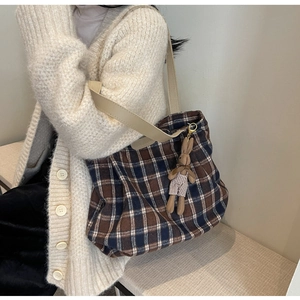 Close-up of a large plaid wool tote bag with a cute brown rabbit plush pendant on it
