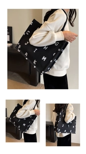 Detail of black canvas tote bag with white letter print and fabric shoulder strap