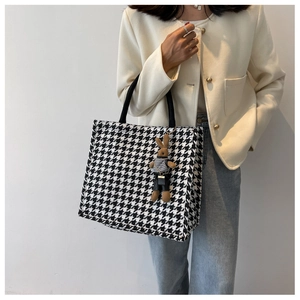 Detail of houndstooth tote bag with a cute brown plush bunny pendant and black handles