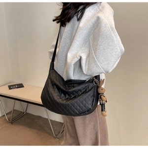 Détail d'un sac matelassé noir avec pendentif lapin marron sur la bandoulière