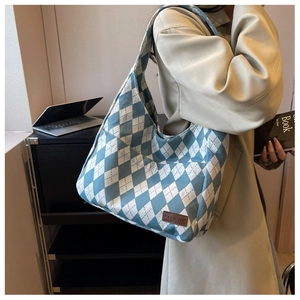 Detail view of a blue and white argyle canvas hobo bag with fashion leather patch