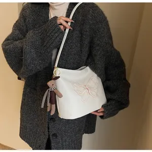 Detailed view of white tote bag with pink butterfly embroidery and rabbit plush charm